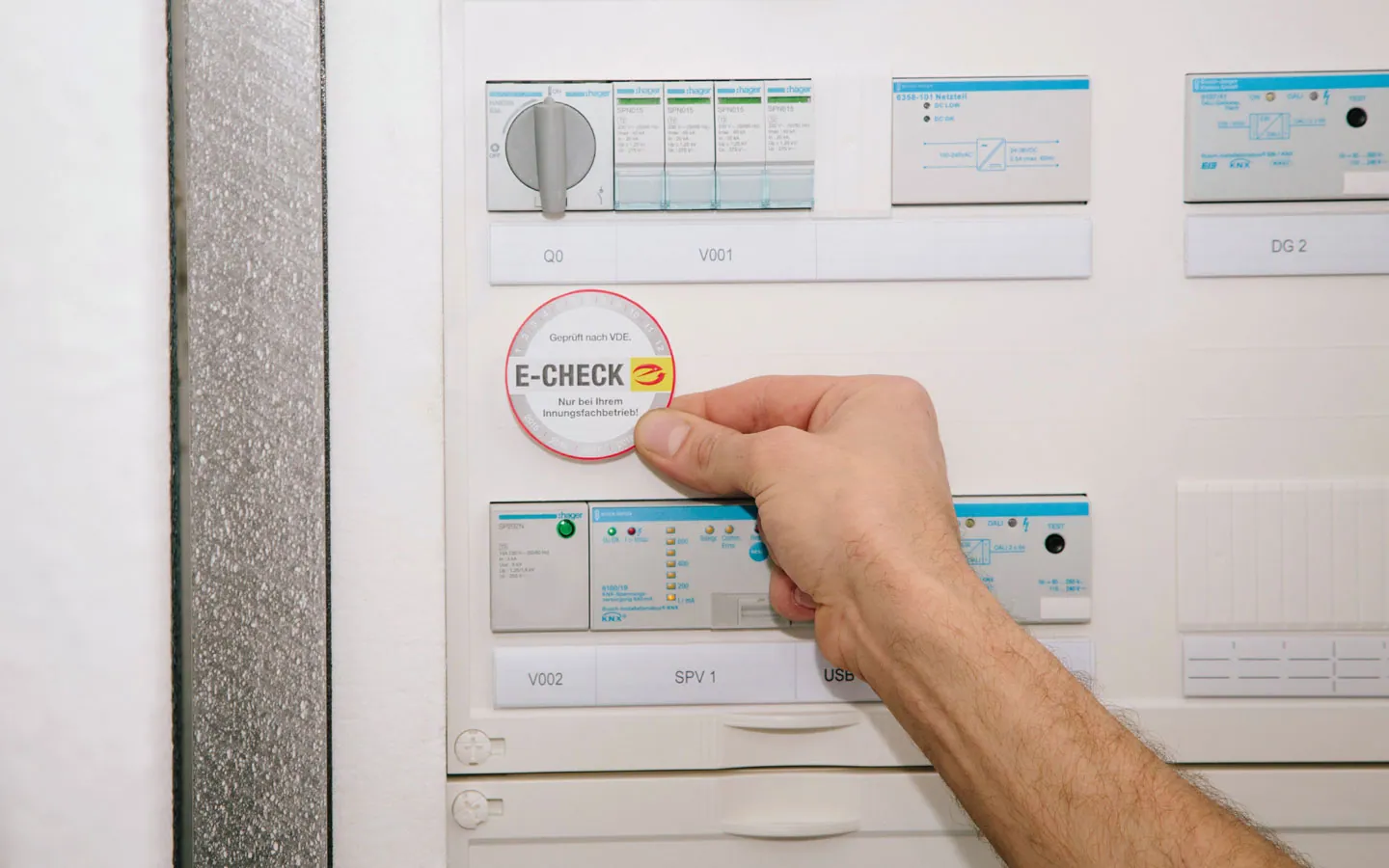 E-CHECK - Mitarbeiter klebt in der Verteilung die E-CHECK Plakette an · Elektro-Diehm
