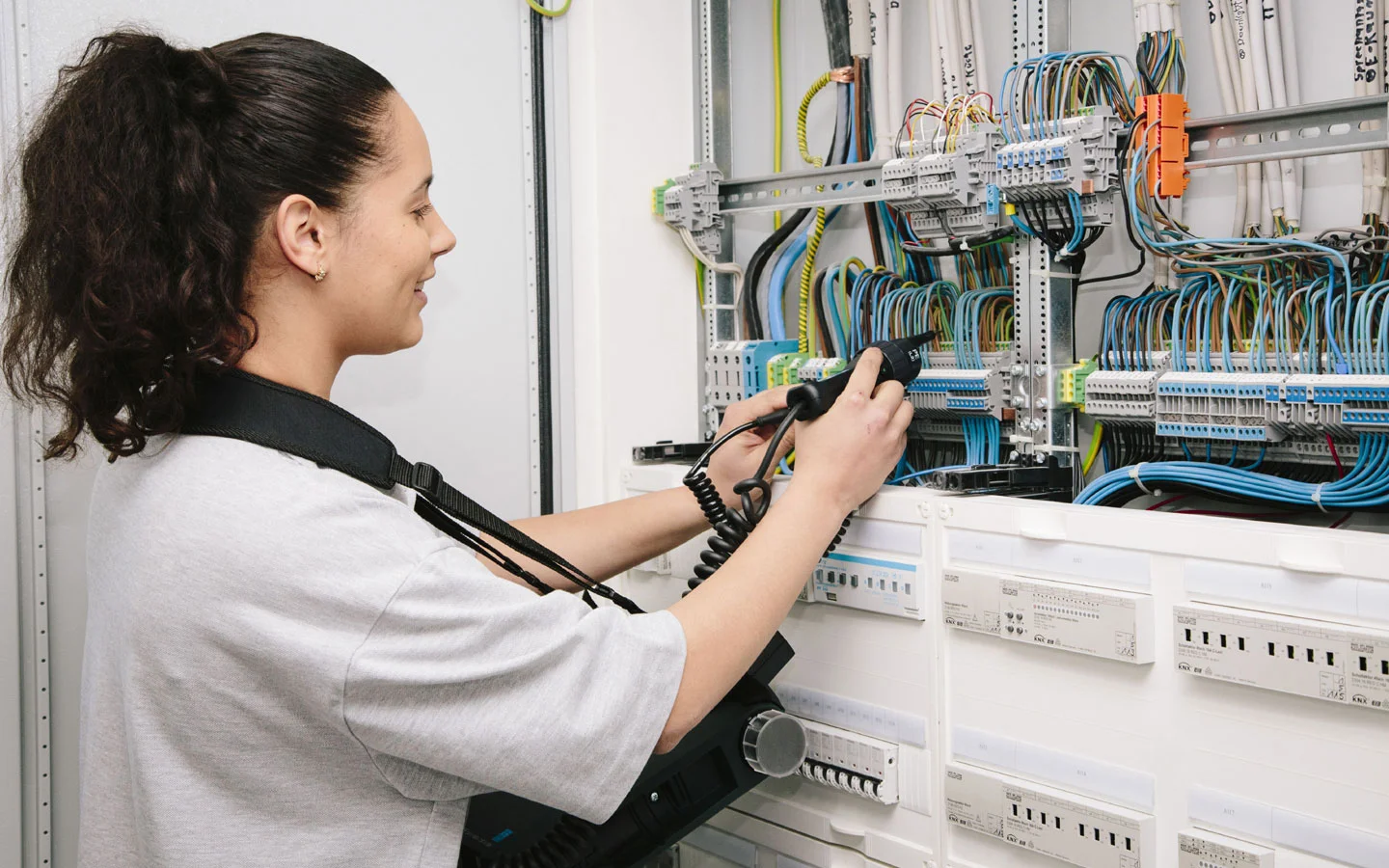 E-CHECK - Mitarbeiterin prüft im Schaltschrank mit einem Meßgerät · Elektro-Diehm