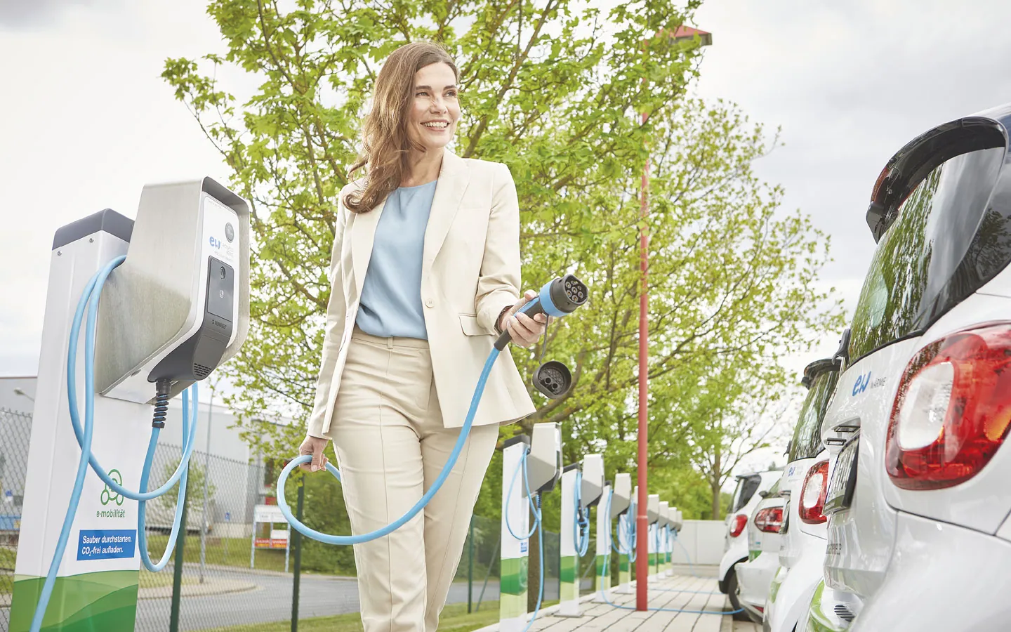 E-Mobilität - Kundin vor Ladestation mit Stecker in der Hand · Elektro-Diehm